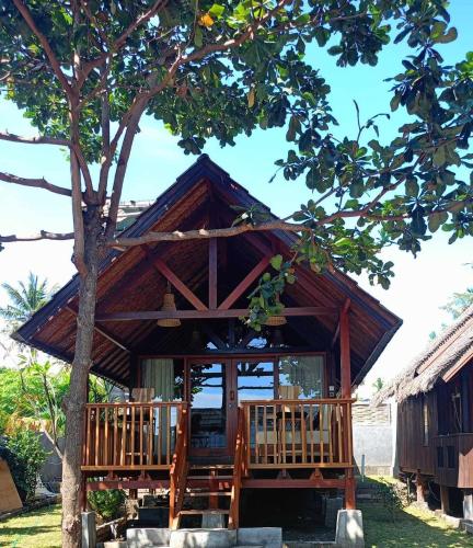 a small house with a tree in front of it at Bintang Tiga Bungalows Gili Air in Gili Air