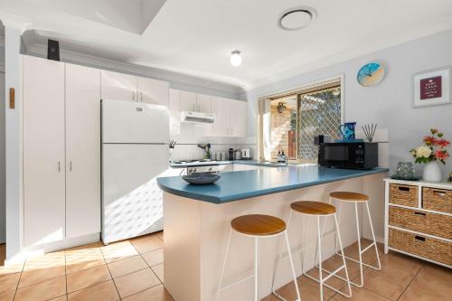 a kitchen with white cabinets and a blue counter top at Coral Villa by Experience Jervis Bay in Huskisson