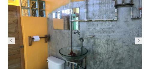 a bathroom with a toilet with a glass bowl on the wall at The Orange House in Big Corn Island