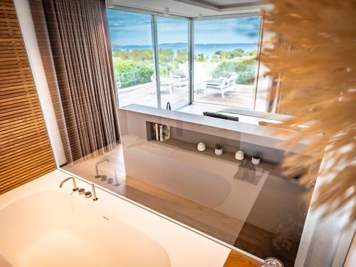 une salle de bain avec baignoire et une grande fenêtre dans l'établissement Porto-Vecchio Palombaggia Villa Azaïtù, à Porto-Vecchio