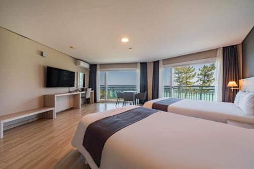a hotel room with two beds and a television at Gyeongpo Soo Hotel in Gangneung