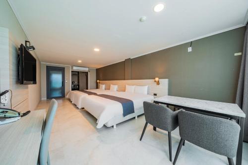 a hotel room with a bed and a table and chairs at Gyeongpo Soo Hotel in Gangneung