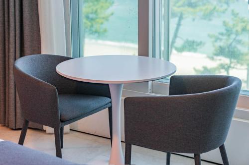 two chairs and a white table and a table and chairs at Gyeongpo Soo Hotel in Gangneung