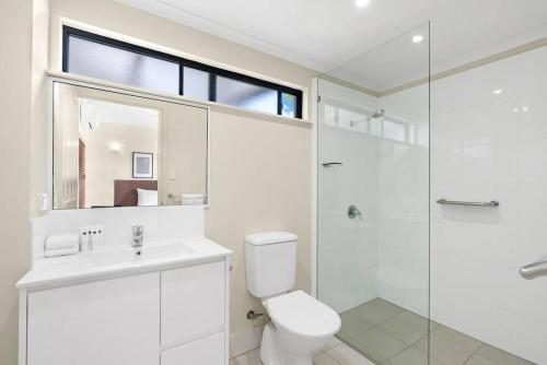 a white bathroom with a toilet and a shower at Tropic Nest - A Relaxed Resort Escape for Couples in Cairns