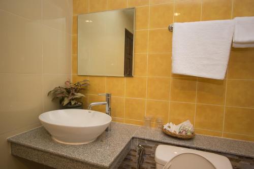 a bathroom with a sink and a toilet and a mirror at Baan Pordeedin in Chiang Rai