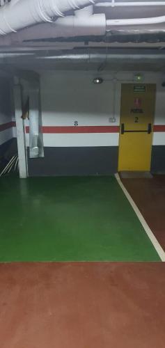 a gym with a yellow door and a green floor at Apartamento en Formigal - Parking Privado Incluido in Formigal