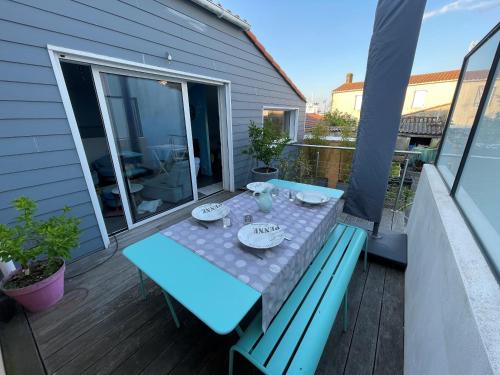 une table bleue et des chaises sur une terrasse avec balcon dans l'établissement Lieutenant Anger - Agreable Maison a 2 pas du quai, à Les Sables-dʼOlonne