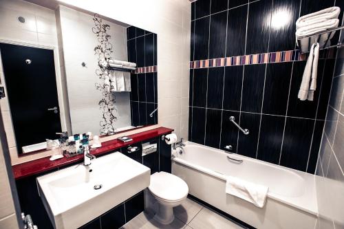 a bathroom with a sink and a toilet and a tub at Crowne Plaza Dublin Blanchardstown by IHG in Blanchardstown