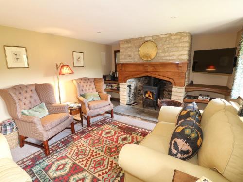 a living room with a couch and a fireplace at Rood Cottage in Burford