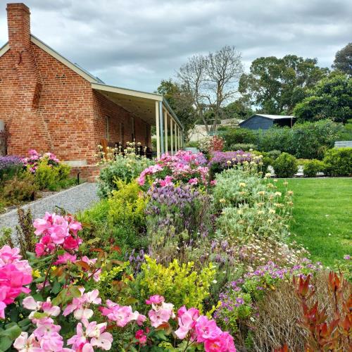 a garden of flowers in front of a brick building at Oxenberry Farm in McLaren Vale
