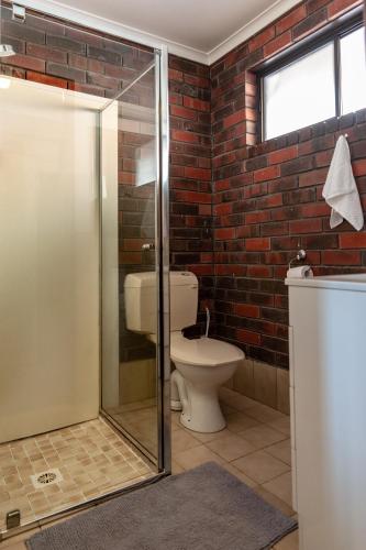 a bathroom with a toilet and a glass shower stall at Sanz Motel Wentworth in Wentworth
