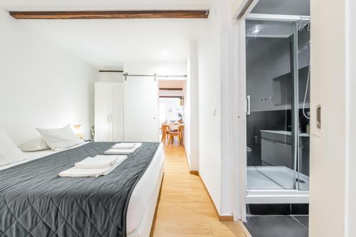 a bedroom with a bed and a bathroom with a shower at Casas do Olival Apartments in Lisbon