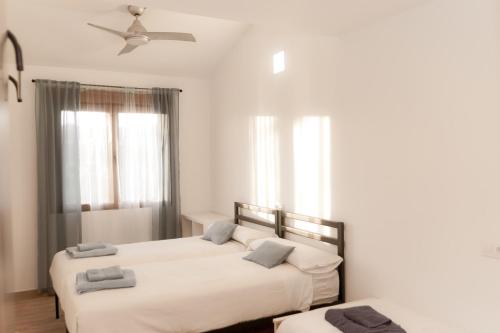 two beds in a room with white walls and windows at La Via Verde in Miguel-Ibáñez