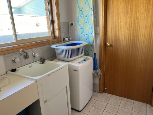 a small kitchen with a sink and a washing machine at Lazy Sails Port - Pets welcome inside WiFi in Robe