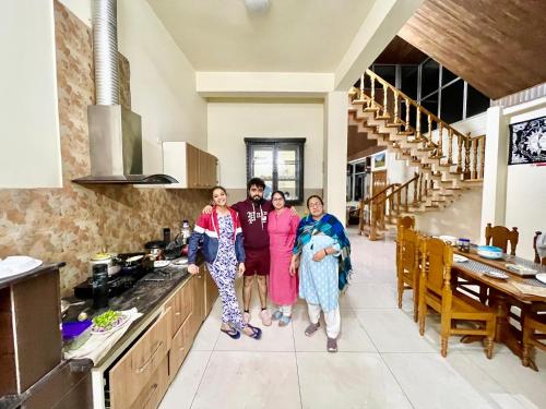 a group of three people standing in a kitchen at The Auriga 3BHK Fully Entair Villa with Bonfire in kasauli I Pvt Stay I Open Air Terrace I Kitchen Livingroom I Lawn Bonfire I Gaming Zone in Kasauli