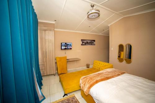 a bedroom with a bed and a yellow chair at Polokwane Estate Lodge & Spa in Polokwane