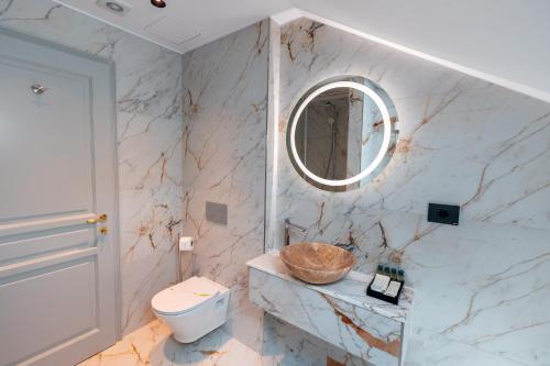 a bathroom with a toilet and a round mirror at Ecletico Villa in Bucharest