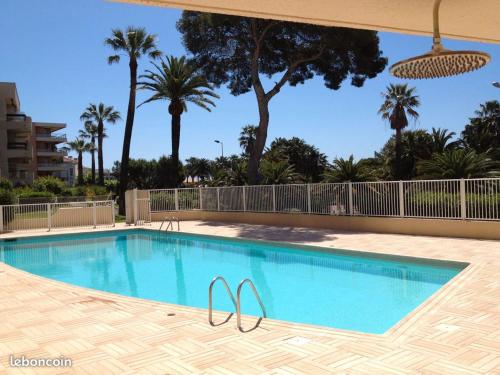 - une piscine dans un complexe avec des palmiers dans l'établissement beaurivage, à Saint-Raphaël