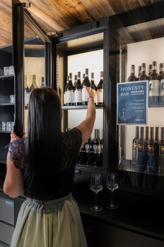 a woman is looking at bottles of wine in a refrigerator at The Gast House Zell am See in Zell am See
