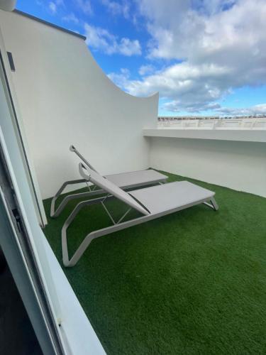 une chaise sur un balcon avec de l'herbe verte dans l'établissement village naturiste - Résidence Le jardin d'éden 