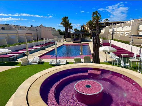 une grande piscine violette avec des chaises et un bâtiment dans l'établissement village naturiste - Résidence Le jardin d'éden 