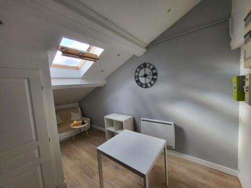 une pièce avec une table et une horloge au mur dans l'établissement Cocon Villeurbanne Charpennes, à Villeurbanne