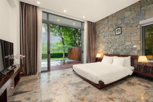 a bedroom with a bed and a stone wall at Flamingo Resort Dai Lai in Ngọc Quang