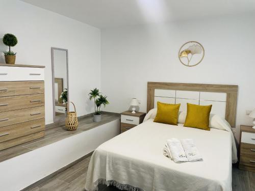 ein weißes Schlafzimmer mit einem großen Bett und gelben Kissen in der Unterkunft Casa Paraiso en Frigiliana in Frigiliana