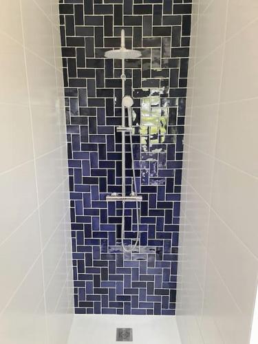 un mur carrelé dans une douche avec un lustre dans l'établissement La Riviera - Site du Futuroscope - 3 chambres, à Chasseneuil-du-Poitou