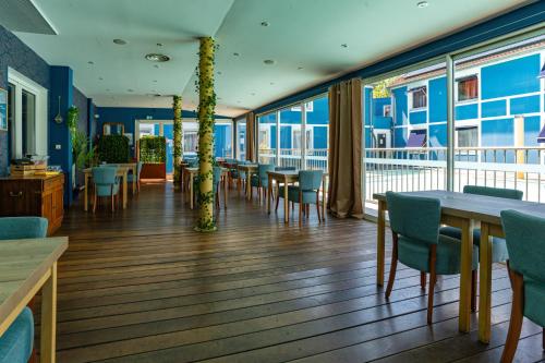 a dining room with tables and chairs and windows at Hotel Argos in Vendenheim