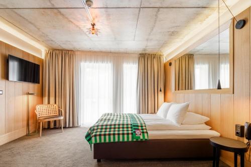 a bedroom with a bed with a green and white blanket at Skostredet Hotel in Bergen