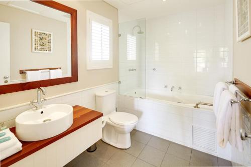 a bathroom with a sink and a toilet and a tub at Caves House Hotel & Apartments Yallingup in Yallingup