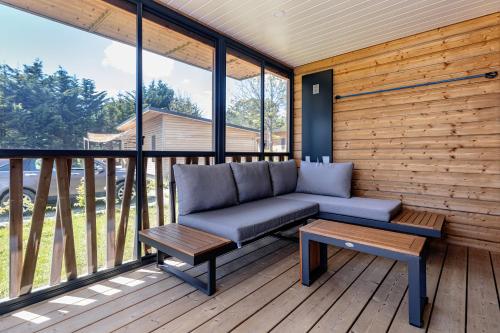 un canapé assis sur une terrasse avec une table dans l'établissement Les Cottages de La Baule : Chalet de standing 7 personnes - Piscine, à Guérande