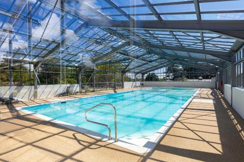 une grande piscine avec un plafond de verre dans l'établissement Les Cottages de La Baule : Chalet de standing 7 personnes - Piscine, à Guérande