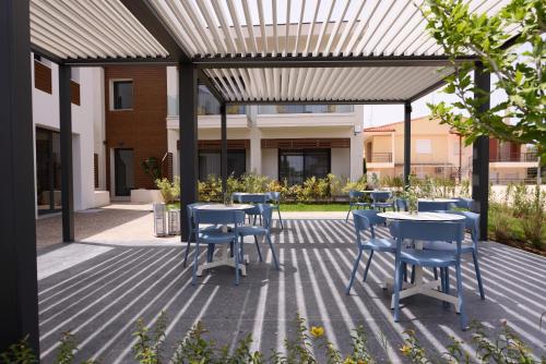 a patio with tables and chairs under a pergola at Falena Luxury Rooms in Kalyves Poligirou