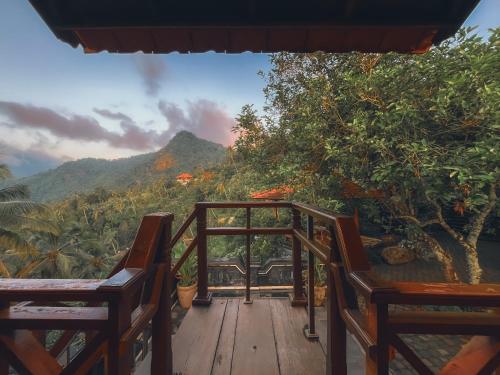a deck with two chairs and a view of a mountain at Rostika Hotel Sekumpul in Buleleng