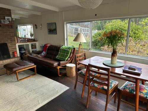 a living room with a couch and a table at Wylah Cottage for a Peaceful Bruny Island Escape with Water Views, Fireplace & Wallabies in Simpsons Bay