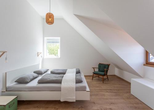 a white bedroom with a bed and a chair at Ferienwohnungen SEEELF - Luv Stay in Überlingen