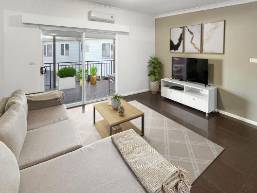 a living room with a couch and a flat screen tv at H2O Holiday Apartments - Unit 10 in North Haven