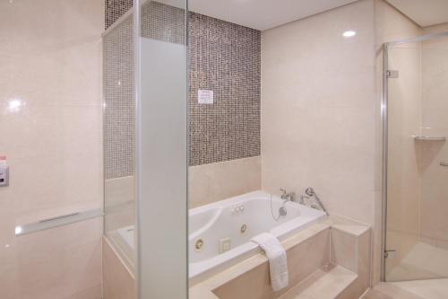 a white bathroom with a tub and a shower at Centum Convention Hotel In Centum in Busan