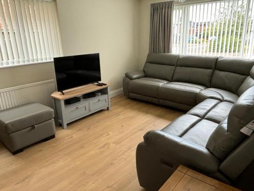a living room with a couch and a flat screen tv at Fabulous Bungalow Norwich in Norwich