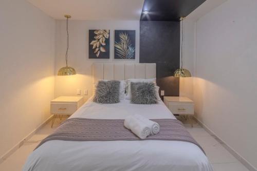 Un dormitorio con una gran cama blanca con dos mesitas de noche. en Apt with Reforma View Pool and Jacuzzi, en Ciudad de México