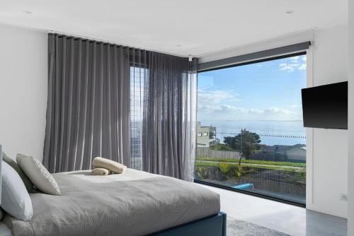 Un dormitorio con una cama y una ventana grande. en Kings View, en San Remo