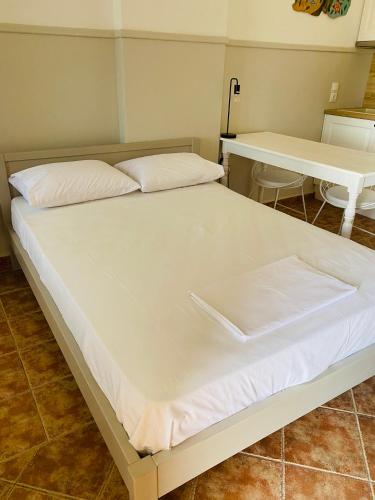 a bed in a room with a table and a white bedsheet at Harmony Seaside Pelion in Platanias