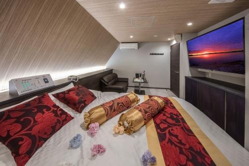a bedroom with a bed with pillows and a flat screen tv at Hotel GEM2 - Adult Only in Sendai