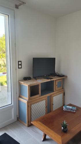 sala de estar con TV en un soporte de madera en Le Truc en plus, accessibles PMR, appartement 45 m2 mitoyen dans une maison avec un autre appartement, en Guérard