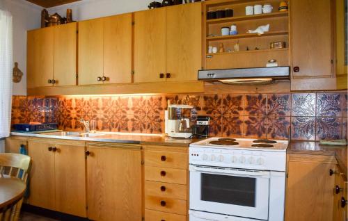 a kitchen with wooden cabinets and a white stove top oven at 4 Bedroom Stunning Home In Löderup in Löderup
