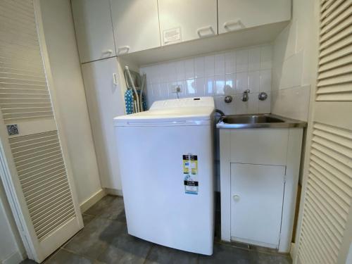 a small kitchen with a white refrigerator and a sink at Osprey Holiday Village Unit 111 in Exmouth