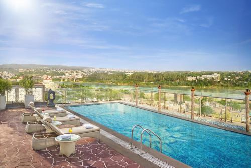 a swimming pool with lounge chairs and a view of the water at Vivanta Jammu City Centre in Jammu