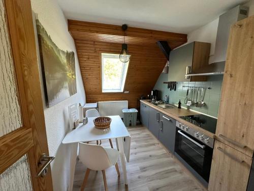 een kleine keuken met een witte tafel en stoelen bij Altes Forsthaus Fischbach in Sankt Andreasberg